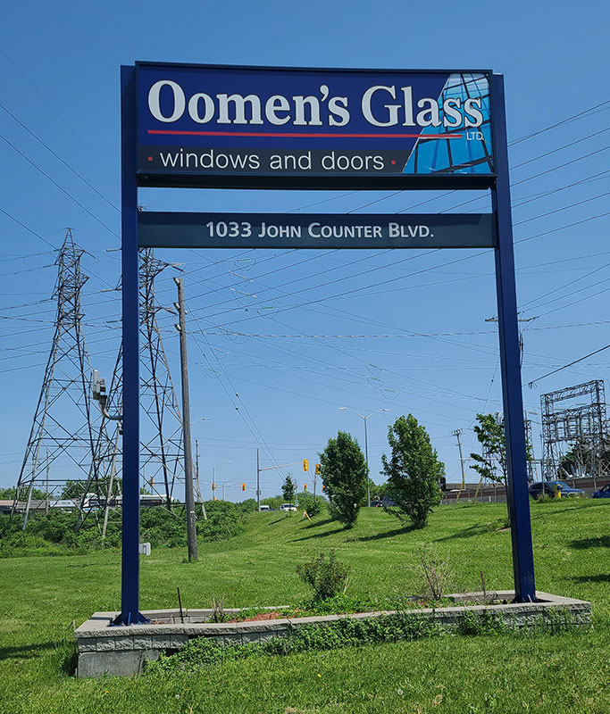 Oomen's Glass sign by roadway with address of 1033 John Counter Blvd. below
