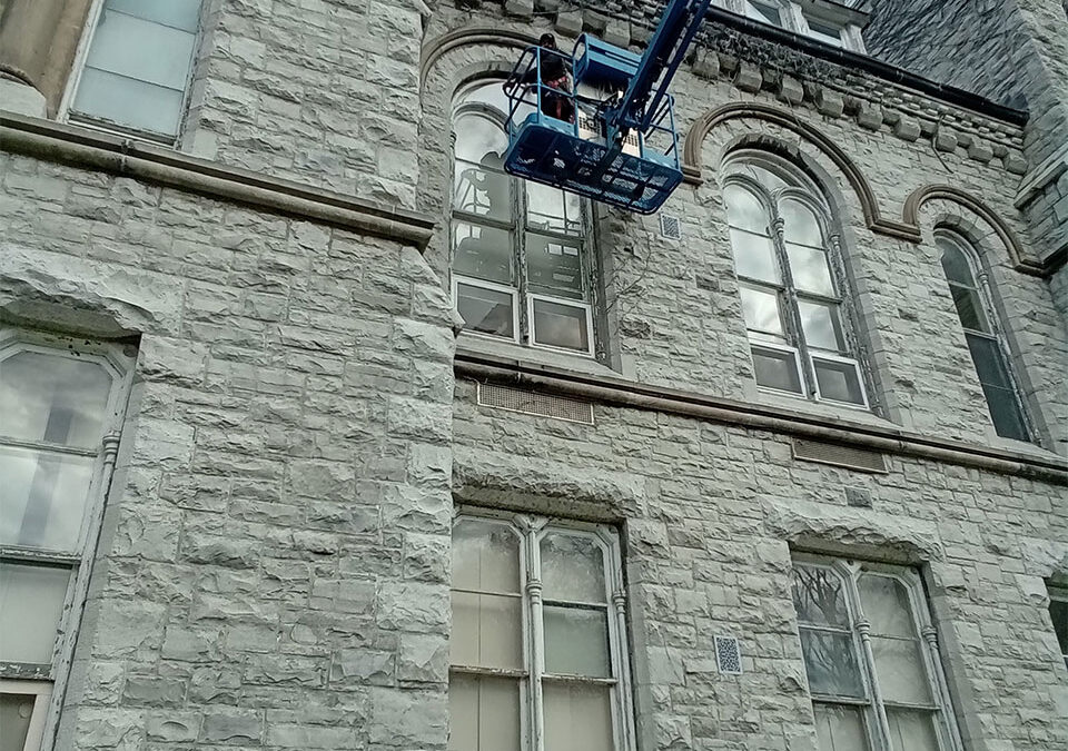 installer using a lift truck to put in a custom cut window pane for a heritage building