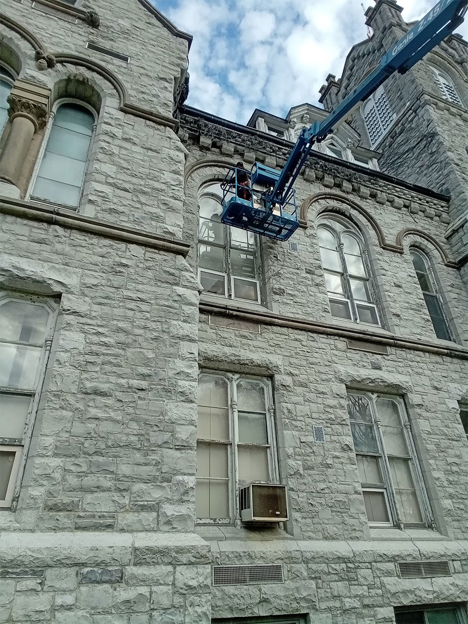 installer using a lift truck to put in a custom cut window pane for a heritage building